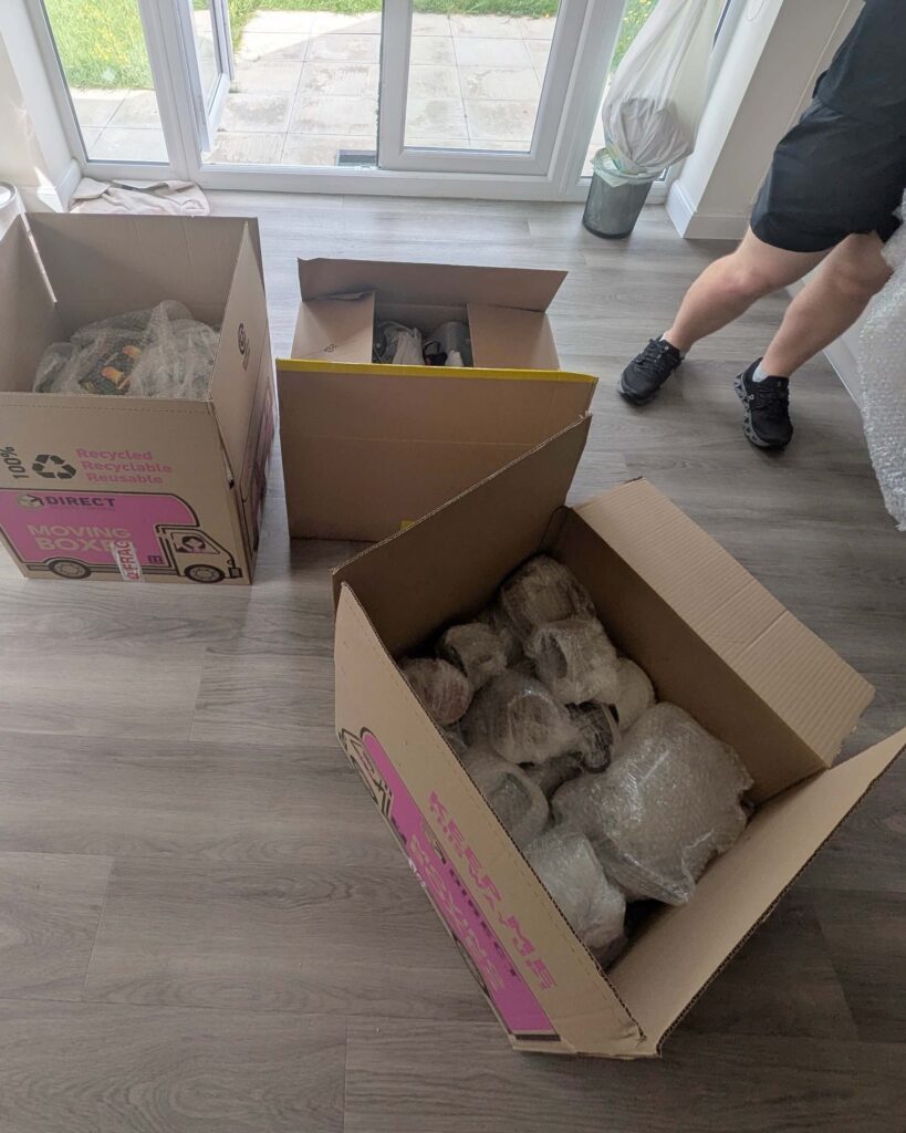 Fragile household items wrapped in bubble wrap and packed into moving boxes