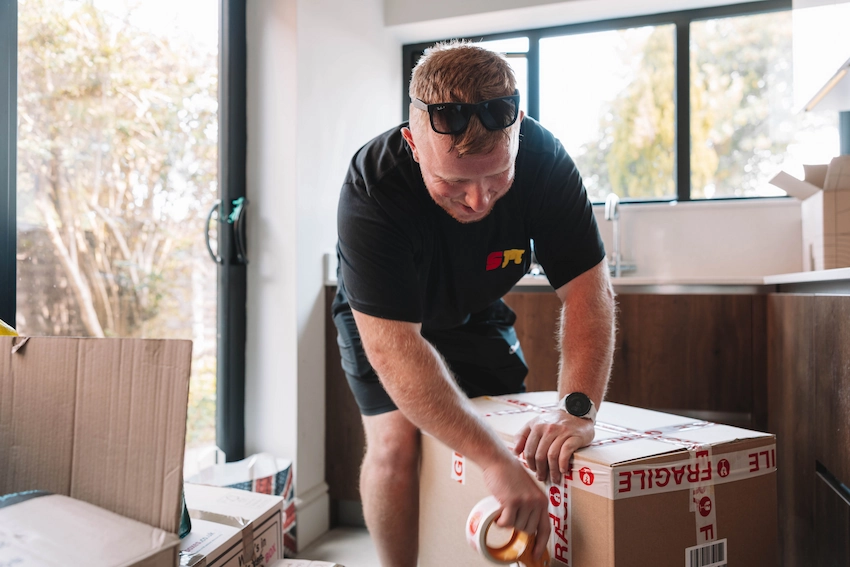 ShiftMate mover carefully sealing a packed box with fragile tape