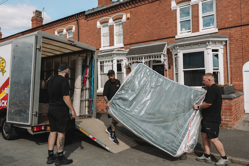 ShiftMate removal team loading protected furniture into a branded removals van