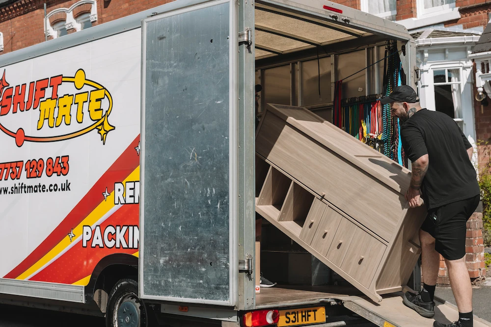 ShiftMate mover loading a wooden cabinet into a branded removals van
