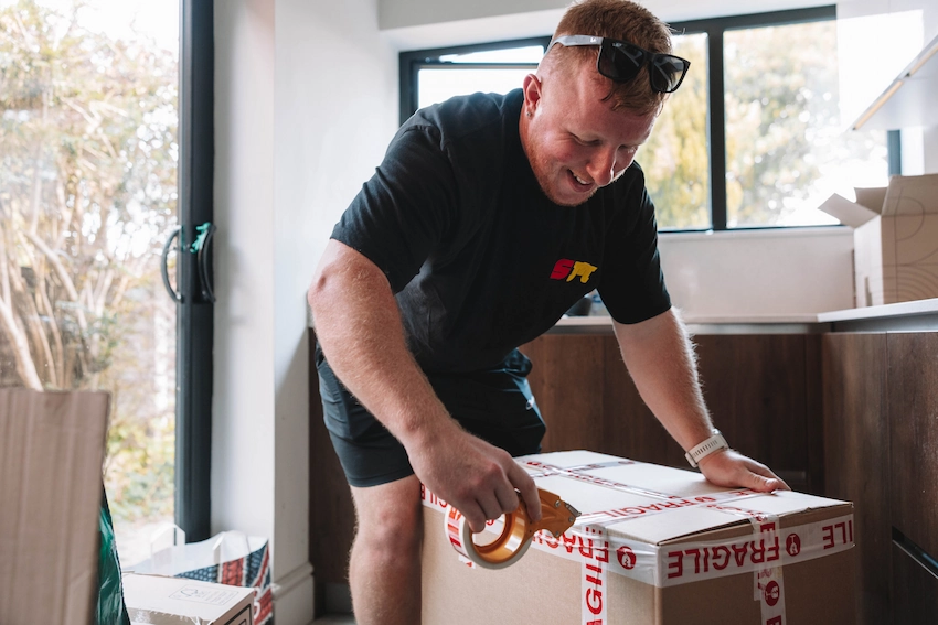 ShiftMate mover sealing a packed box with fragile tape