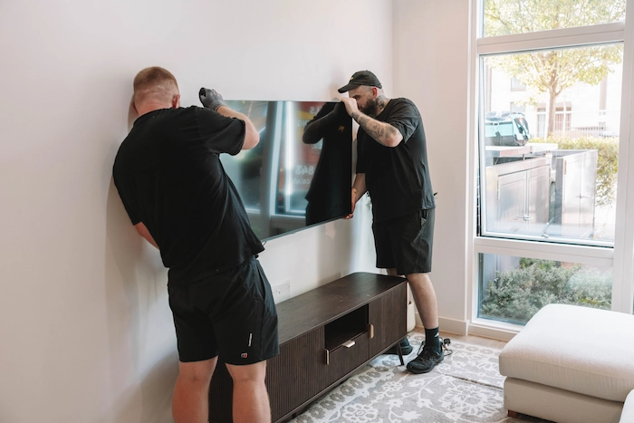 Two ShiftMate movers positioning a television inside a customer’s home