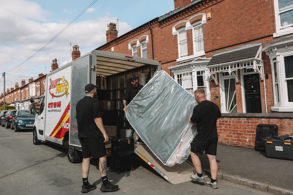 ShiftMate removal team loading a protected mattress into a branded removals van