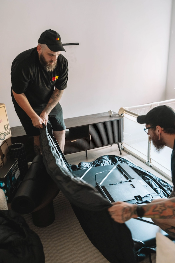 Two ShiftMate movers placing a television inside a padded protective cover